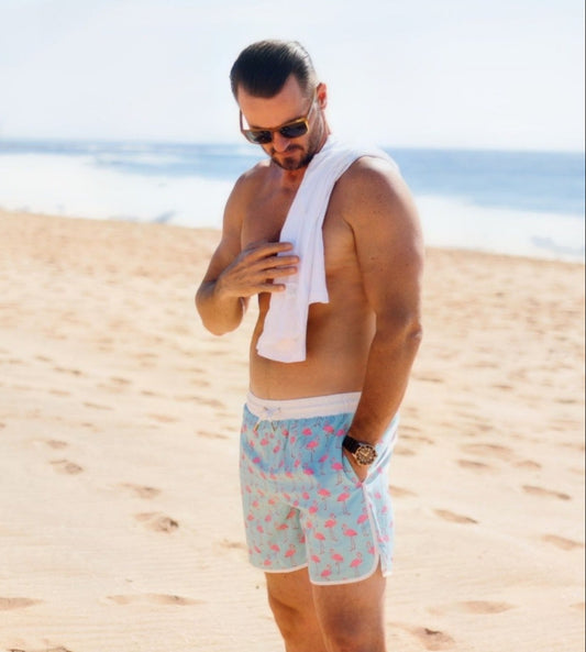 man wearing flamingo pattered swim shorts
